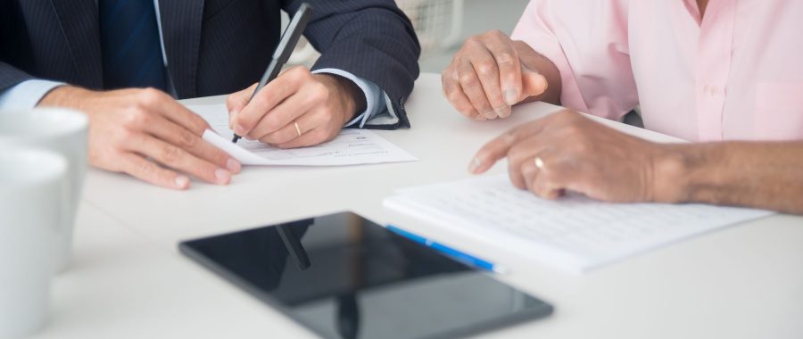Deux personnes signent des documents autour d'une table de travail