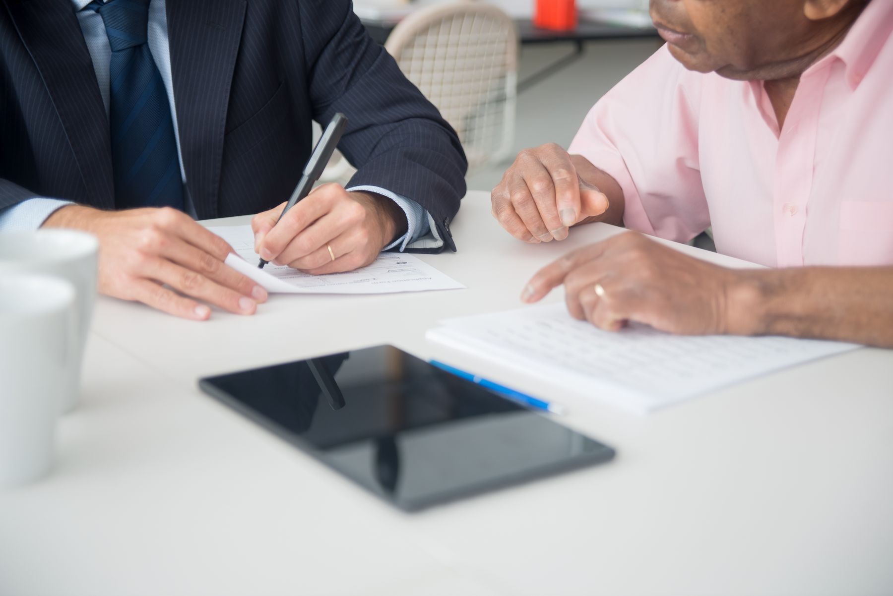 Deux personnes signent des documents autour d'une table de travail
