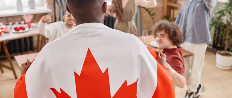 Une personne drapée dans le drapeau canadien célèbre entourée d'amis
