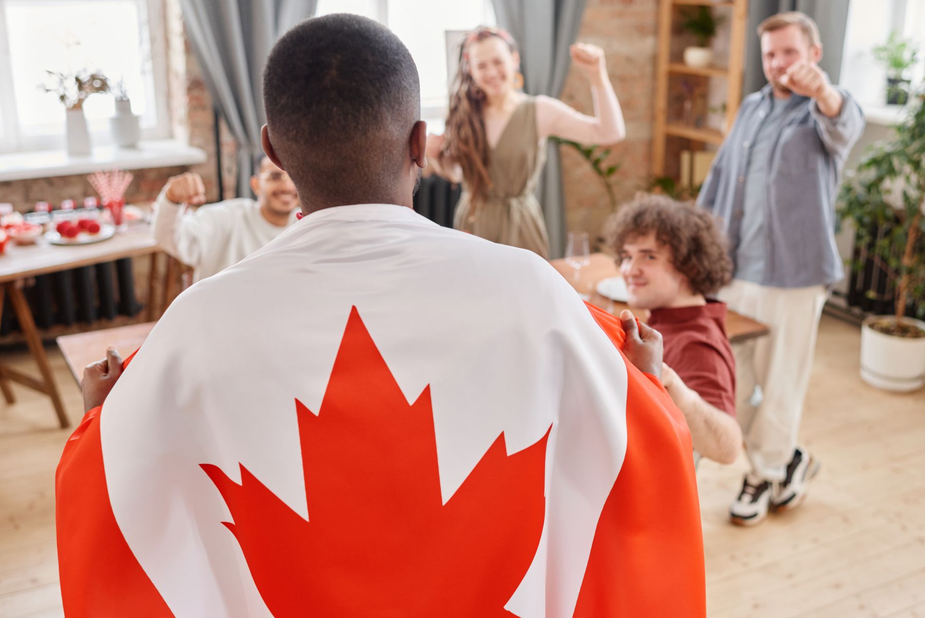Une personne drapée dans le drapeau canadien célèbre entourée d'amis